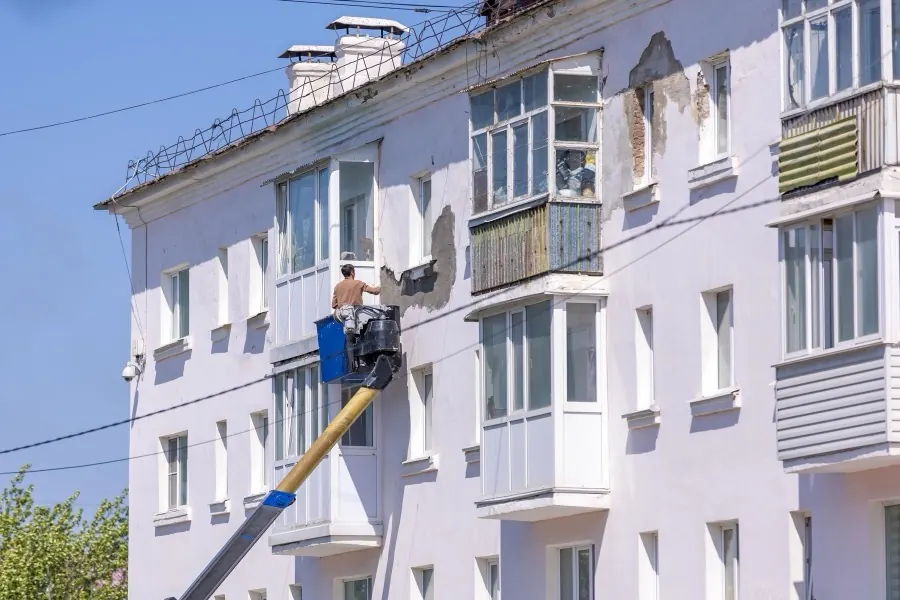 Façadier en nacelle reprenant l'enduit abîmé d'un immeuble.