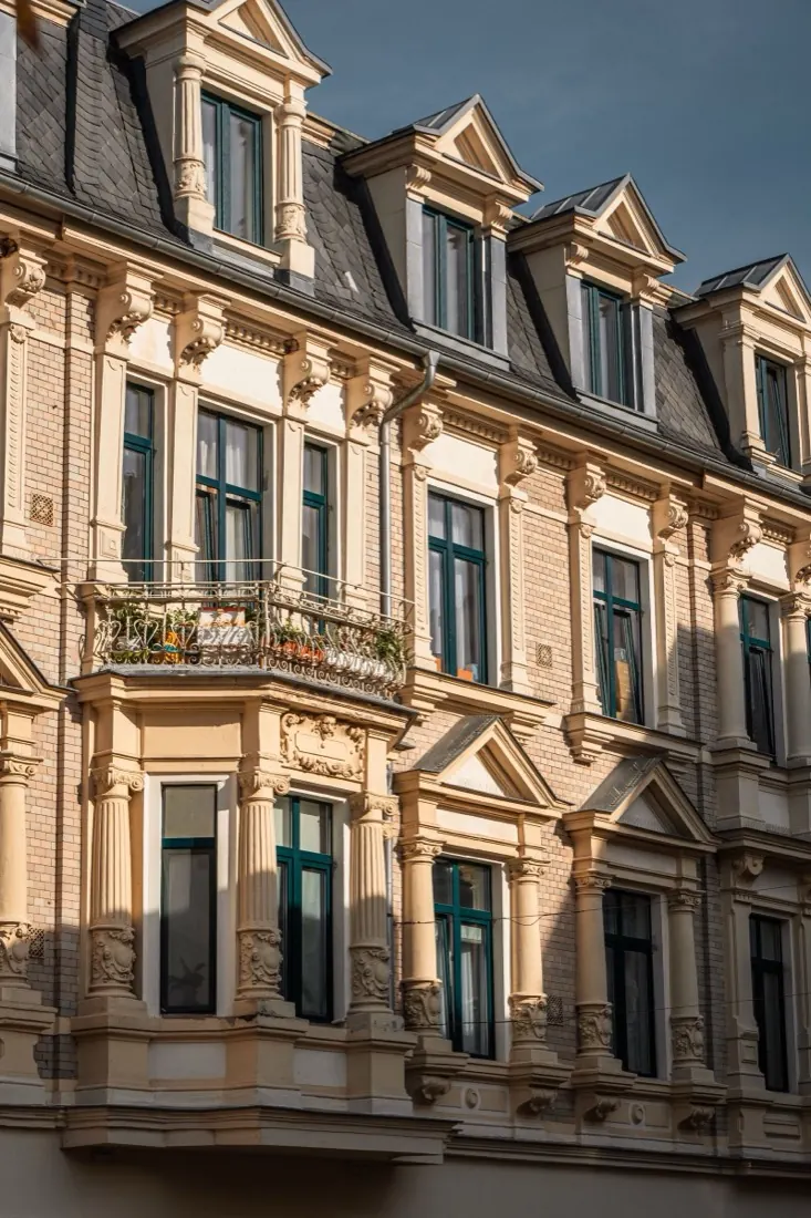 Façade ancienne ravalée et repeinte, moulures et corniches soulignées par la lumière du soir.